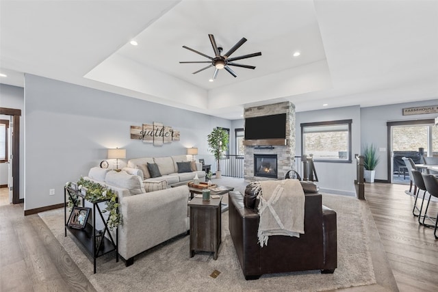 living room featuring light wood finished floors, a raised ceiling, and a ceiling fan