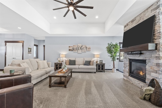 carpeted living room featuring a stone fireplace, recessed lighting, a ceiling fan, and baseboards