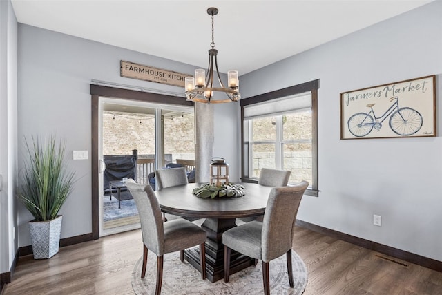 dining space featuring a notable chandelier, visible vents, baseboards, and wood finished floors