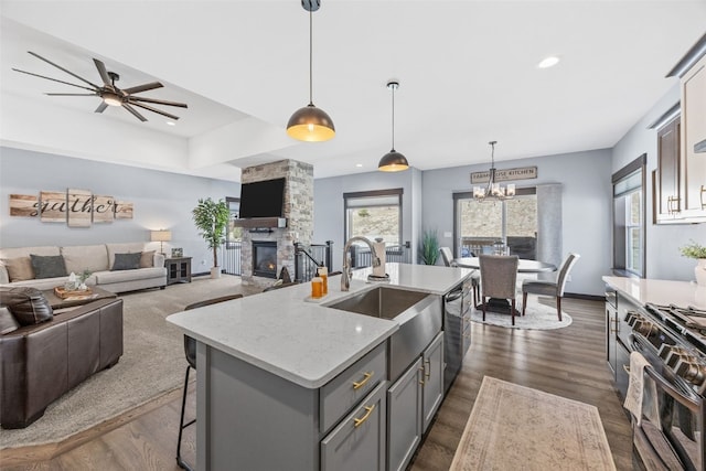 kitchen with gray cabinets, black gas range, a sink, stainless steel dishwasher, and open floor plan