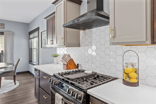 kitchen with gas stove, dark wood finished floors, light countertops, wall chimney exhaust hood, and backsplash