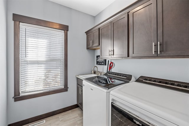 clothes washing area with baseboards, visible vents, washing machine and clothes dryer, cabinet space, and a sink