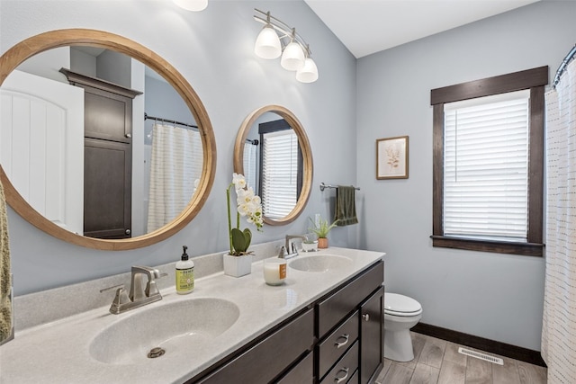 bathroom featuring visible vents, toilet, wood finished floors, and a sink