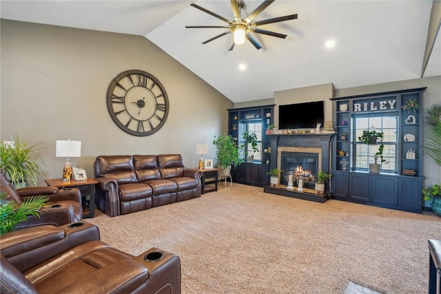 carpeted living room with a glass covered fireplace, ceiling fan, and vaulted ceiling