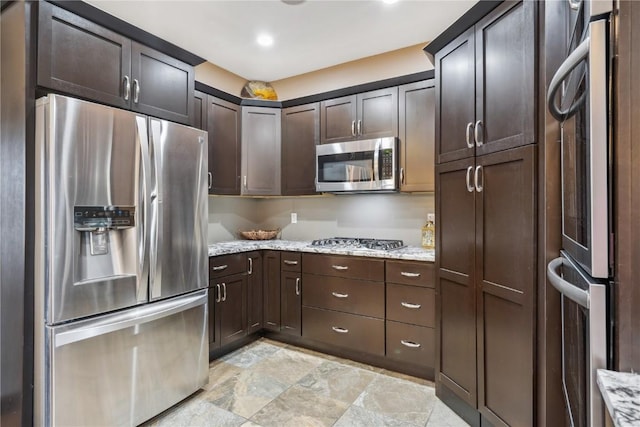 kitchen with stainless steel appliances, light stone countertops, dark brown cabinets, and stone finish flooring