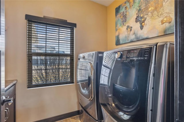 clothes washing area featuring baseboards, separate washer and dryer, and laundry area