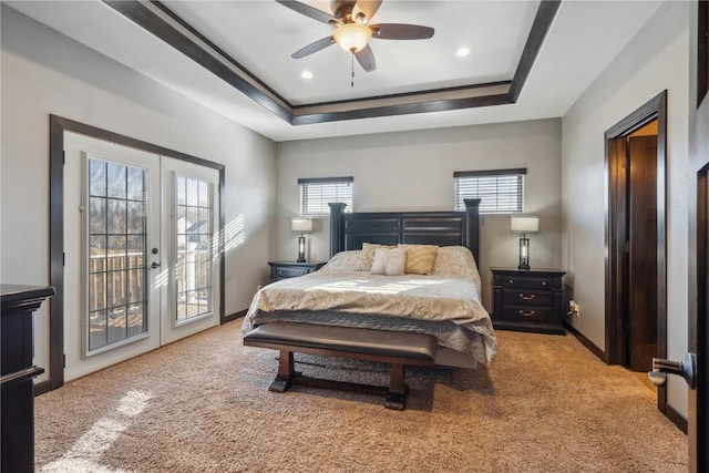 bedroom with french doors, a raised ceiling, multiple windows, and access to exterior