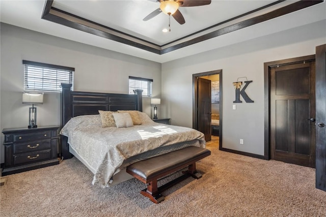 bedroom with a tray ceiling, light colored carpet, baseboards, and ceiling fan