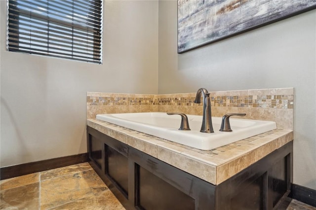 bathroom featuring a sink, baseboards, and stone tile floors