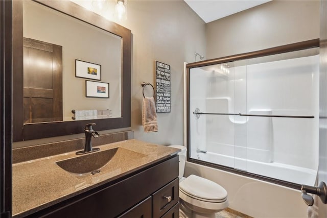 bathroom featuring vanity, toilet, and bath / shower combo with glass door