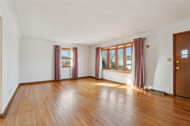 unfurnished living room with baseboards, visible vents, and wood-type flooring