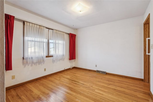 unfurnished room with visible vents, light wood-style flooring, and baseboards