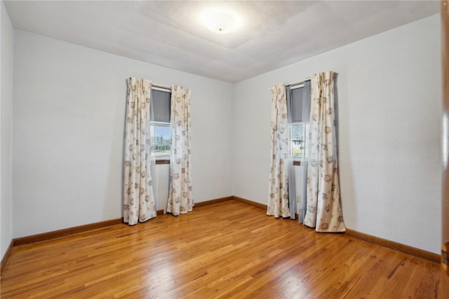 spare room with baseboards and light wood finished floors