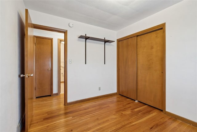 unfurnished bedroom with a closet, baseboards, and light wood finished floors