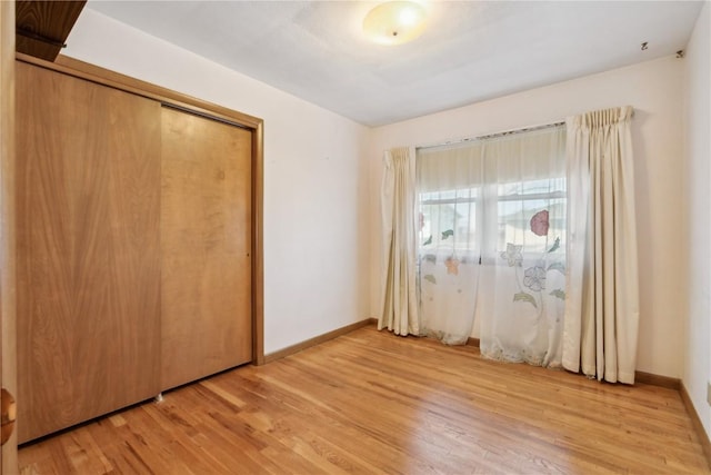 unfurnished bedroom featuring a closet, baseboards, and light wood-style floors