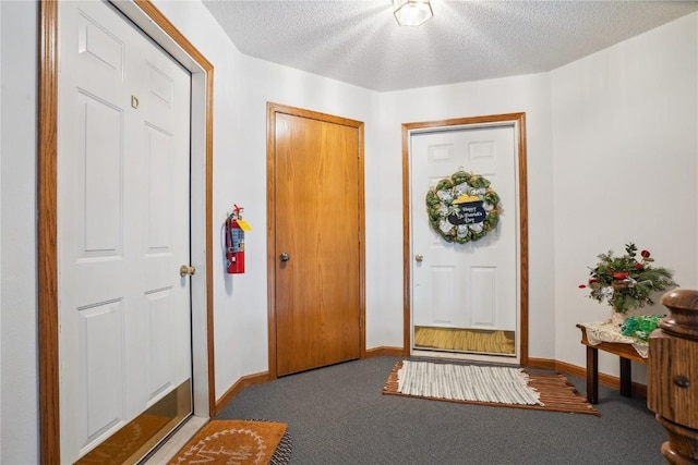 foyer entrance featuring baseboards, a textured ceiling, and carpet flooring