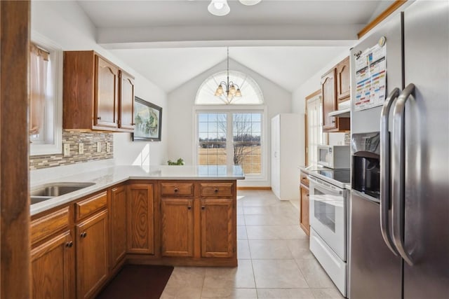 kitchen with light countertops, lofted ceiling, a peninsula, an inviting chandelier, and white appliances