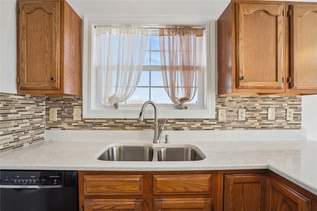 kitchen with black dishwasher, brown cabinetry, backsplash, and a sink