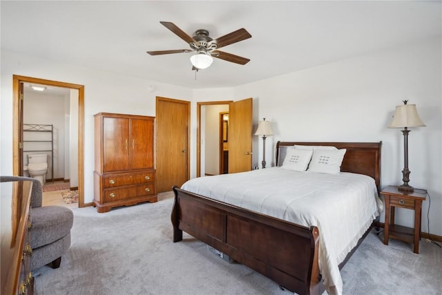 bedroom featuring baseboards, light carpet, ensuite bathroom, and a ceiling fan