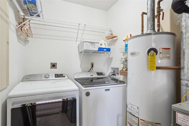 laundry area with gas water heater, washing machine and dryer, and laundry area