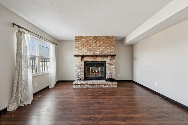 unfurnished living room with a fireplace, a textured ceiling, baseboards, and hardwood / wood-style flooring