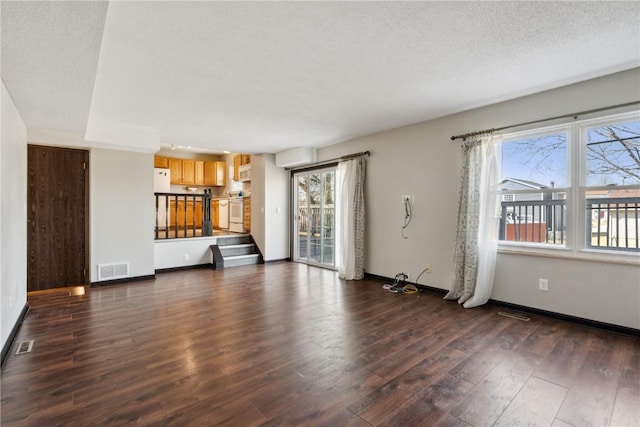 unfurnished living room featuring visible vents, dark wood-style flooring, a textured ceiling, baseboards, and stairs