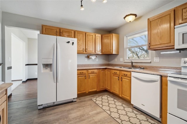 kitchen with a sink, white appliances, light wood-style flooring, and light countertops