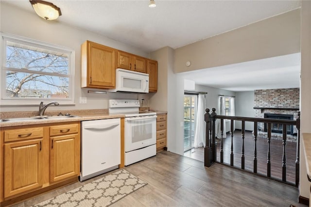 kitchen featuring white appliances, a large fireplace, light countertops, and a sink