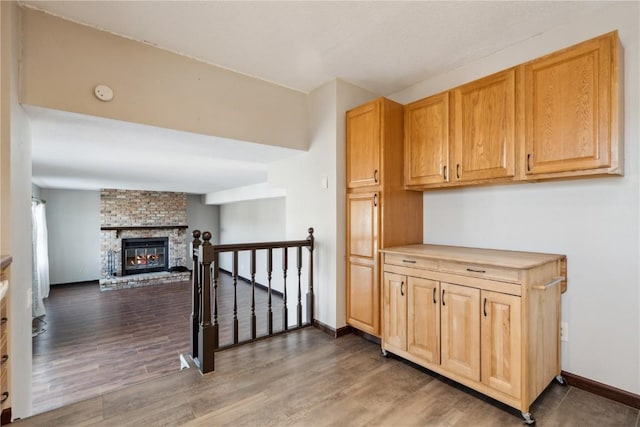 kitchen with a fireplace, baseboards, and wood finished floors