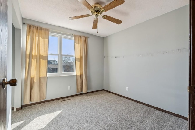 carpeted empty room with ceiling fan, baseboards, and a textured ceiling