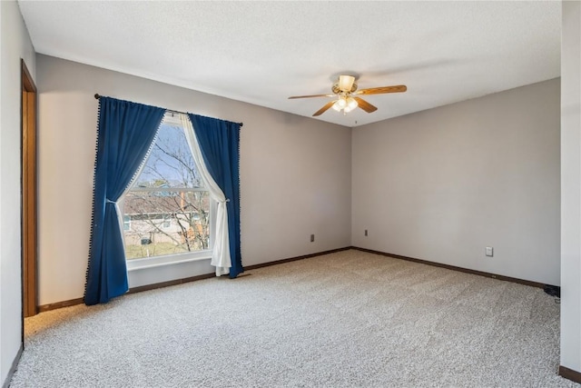 empty room featuring carpet flooring, a ceiling fan, baseboards, and a textured ceiling