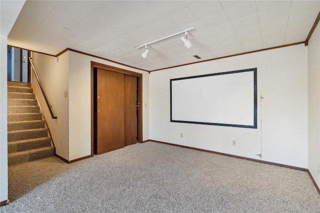 cinema room featuring rail lighting, carpet, baseboards, and ornamental molding