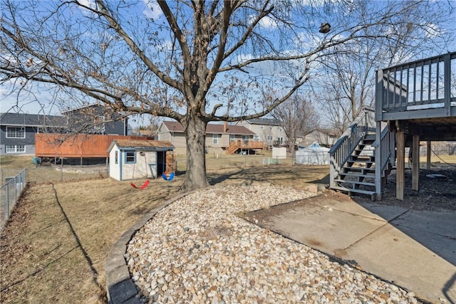 view of yard with fence, stairway, a storage shed, a deck, and an outbuilding