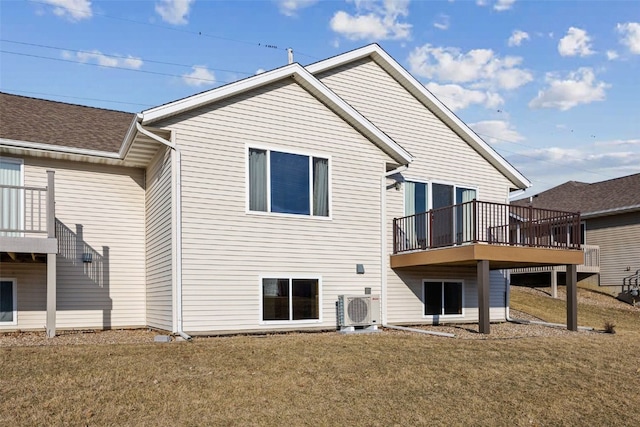 rear view of property featuring ac unit, a lawn, and roof with shingles