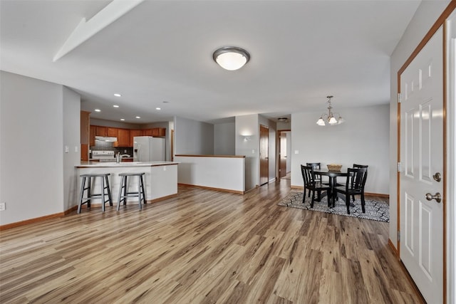 interior space with recessed lighting, baseboards, an inviting chandelier, and light wood-style flooring