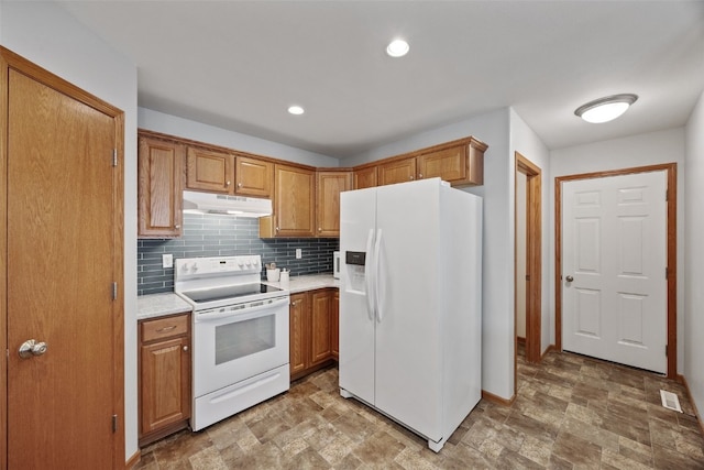 kitchen with visible vents, under cabinet range hood, backsplash, white appliances, and light countertops