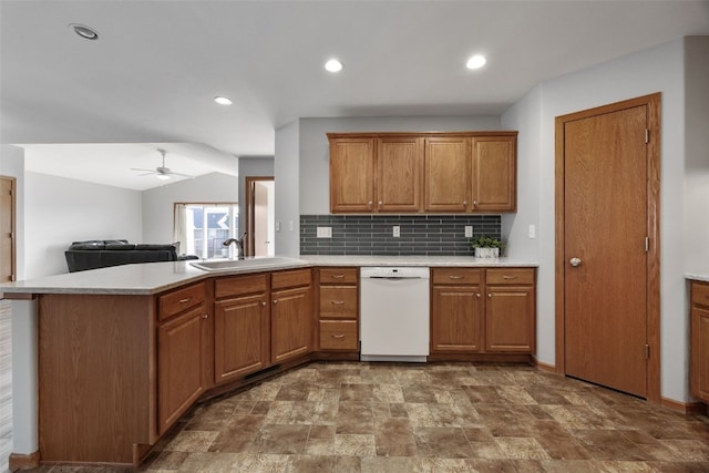 kitchen with dishwasher, light countertops, brown cabinetry, and a sink