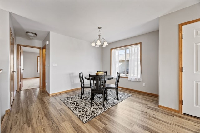 dining space featuring a chandelier, light wood-type flooring, and baseboards