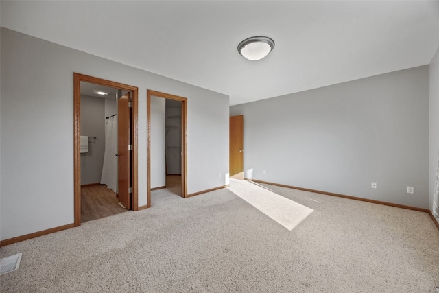 unfurnished bedroom featuring visible vents, a closet, carpet, baseboards, and a spacious closet