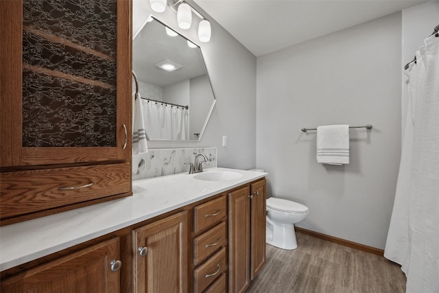 bathroom with toilet, vanity, baseboards, and wood finished floors