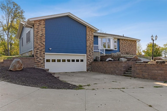 2261 Creekside Rd, Springville, IA 52336 - view of home's exterior with concrete driveway, an attached garage, and brick siding