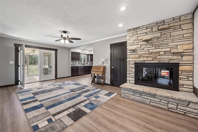 2261 Creekside Rd, Springville, IA 52336 - unfurnished living room featuring a ceiling fan, a fireplace, a textured ceiling, wood finished floors, and recessed lighting