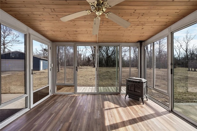 unfurnished sunroom with wooden ceiling, ceiling fan, a wood stove, and vaulted ceiling