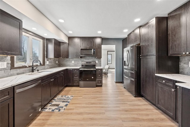 kitchen featuring light stone counters, tasteful backsplash, appliances with stainless steel finishes, light wood finished floors, and dark brown cabinets