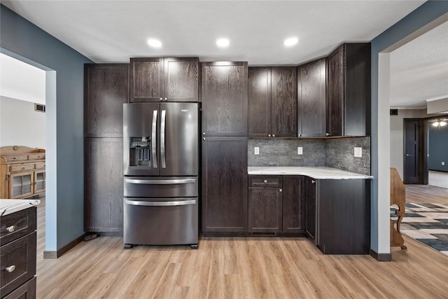 kitchen featuring stainless steel fridge, light wood-style floors, dark brown cabinets, and light countertops