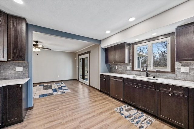 kitchen with dark brown cabinets, baseboards, dishwasher, light wood-style floors, and a sink