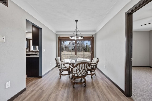 dining space with baseboards, visible vents, and light wood-type flooring