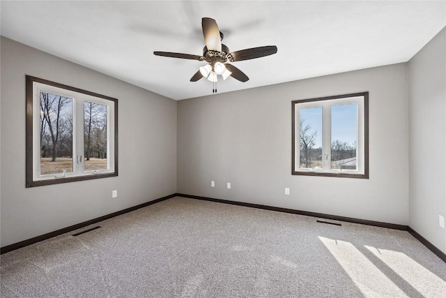 carpeted spare room featuring visible vents, baseboards, and a ceiling fan