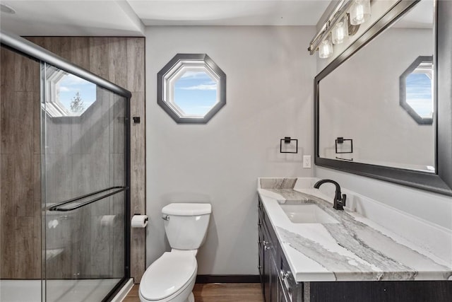 bathroom with baseboards, toilet, a stall shower, wood finished floors, and vanity