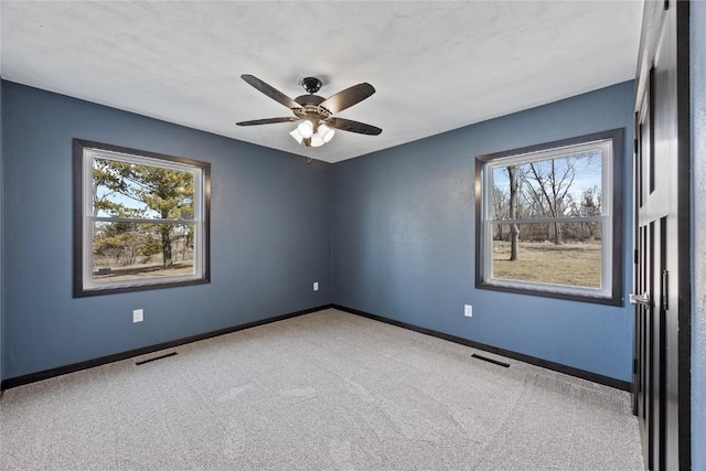 empty room featuring carpet floors, baseboards, and ceiling fan